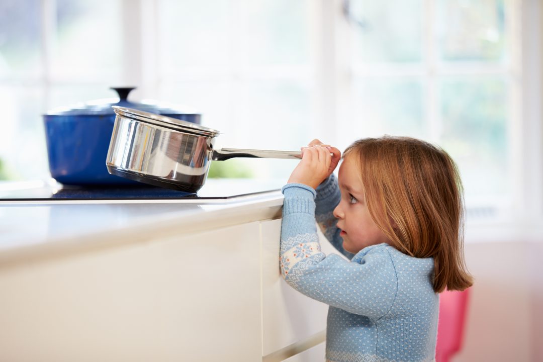 Photo of a child taking a saucepan off a hot stove
