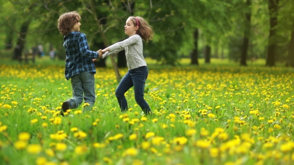 Two children spinning and dancing around the grass